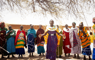 Group of Maasai women sing in Tanzania together wearing brightly colored clothes.
