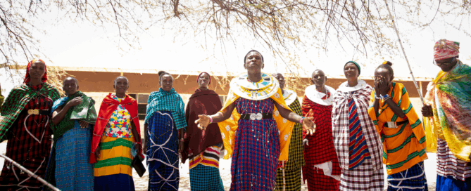 Group of Maasai women sing in Tanzania together wearing brightly colored clothes.