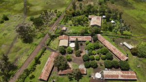 Aerial view of a rural farm with red-roofed buildings, dirt roads, and green fields.